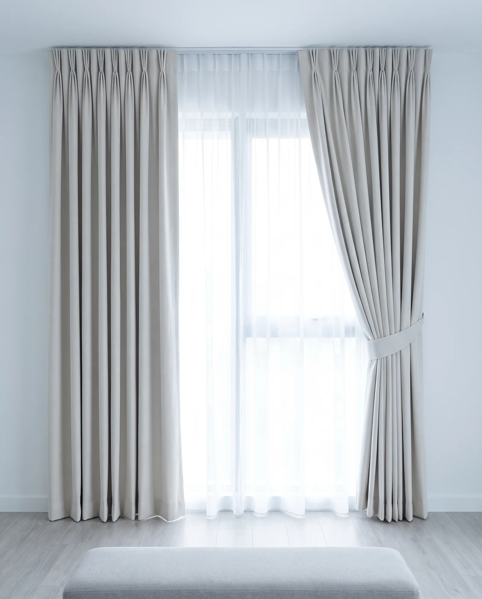 Pale greige pinch-pleat drapes with a sheer lining